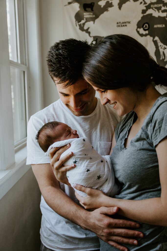 A man embracing a woman as she holds their newborn baby.