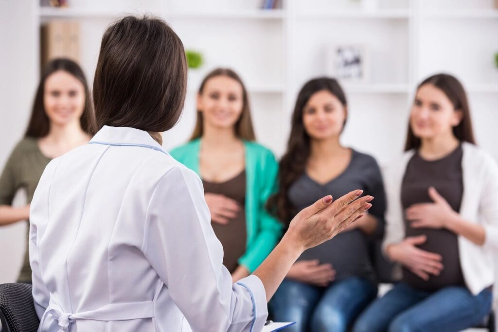 Doctor discussing pregnancy, labor and birth with a group of pregnant people. 